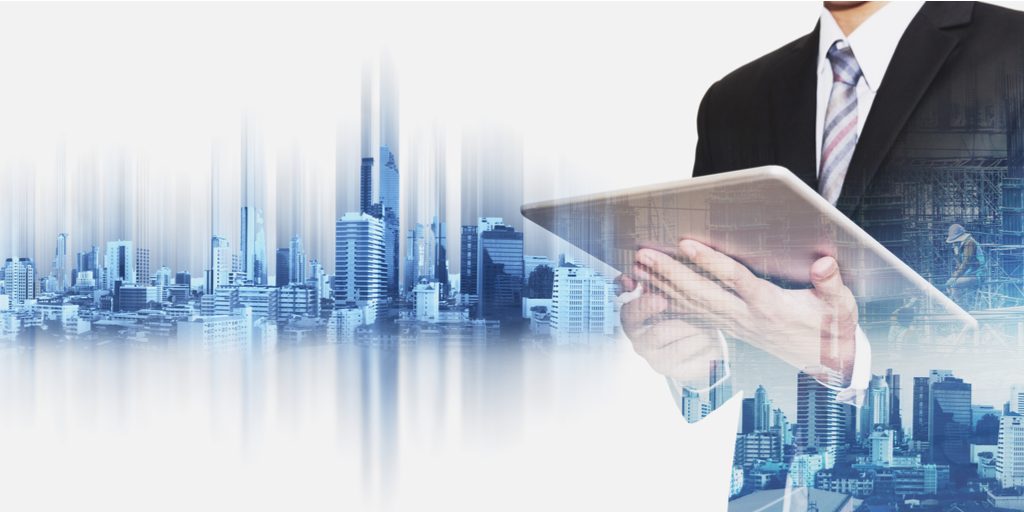 Businessman holding a tablet with composited city skyline behind him